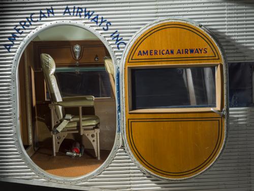 View of the exit door and cabin of a plane. In the plane there is a passenger seat. 