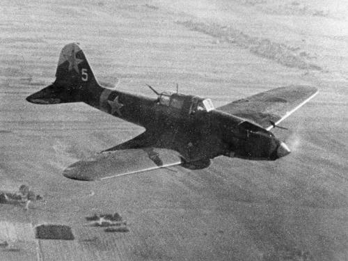 Airplane flies over what appears to be farmland. 