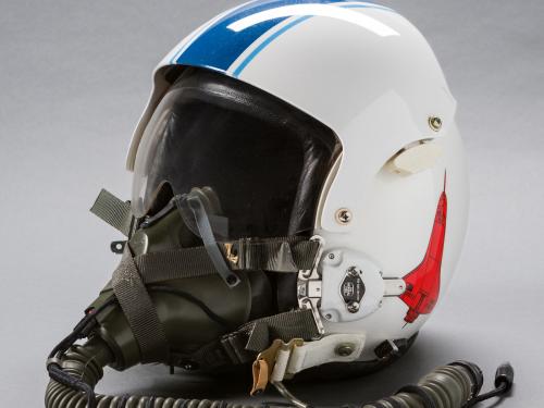 A flight helmet photographed in a studio setting.