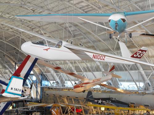 Full view of a streamlined red and white aircraft suspended from the ceiling. The number 33 is on the tail and the code NIIOOZ is on the side.