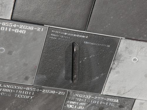 A close-up of several dark tiles with embossed alphanumeric codes and a single metallic handle, suggesting a system of organization or identification, possibly for inventory or categorization purposes.