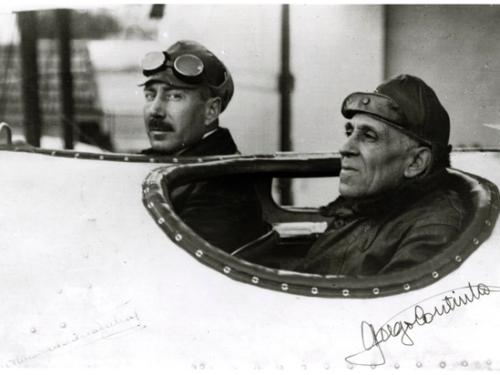 Artur de Sacadura Cabral (on the left) and Gago Coutinho (on the right), both of whom are Portuguese male naval aviators, inside the cockpit of an aircraft.