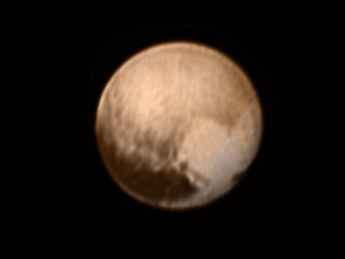 Disk view of Pluto, showing a brown planet with a heart-like shape coloration on the lower right quadrant of the dwarf planet.