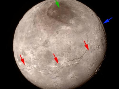 A disk view of Charon, Pluto's largest moon, which has a gray and brown color. Different colored arrows highlight various geographical features on the planet.