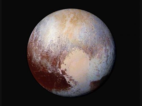 Disk view of Pluto with false colors to emphasise the different topographies of the planet. A heart shape is visible on the lower right quadrant. 