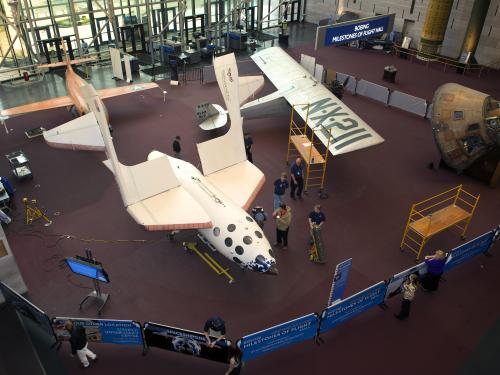 The SpaceShipOne, a white, experimental commercial spacecraft, is placed back into the Boeing Milestones of Flight Hall following a restoration during the Hall's renovation. The spacecraft's wings are folded upwards.