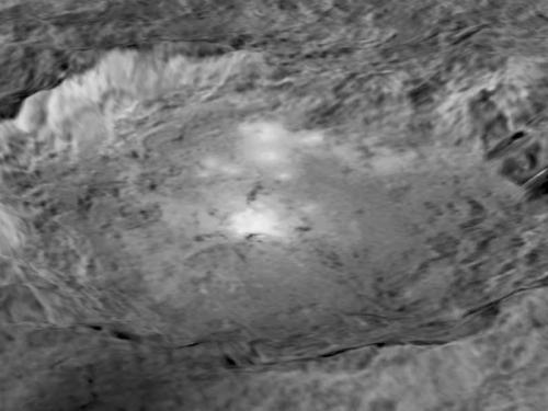 Black and white, close-up view of a large crater on Ceres, a dwarf planet. The crater has a shape similar to an oval.