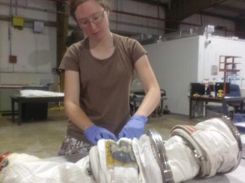 A white female Museum intern builds part of a spacesuit.