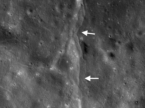 View of fault scarps, where land on one side has moved vertically, on the Moon. White arrows point out the fault line.