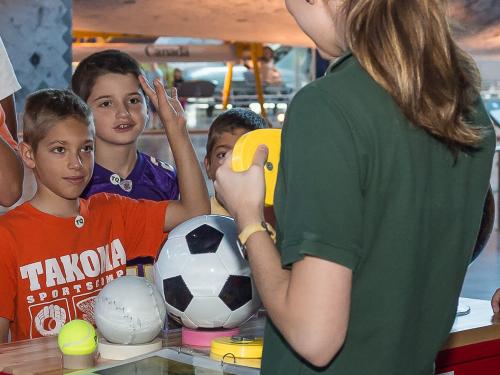 A Museum employee teaches multiple children about Mars as part of an astronaut game.