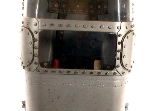 Small, metal capsule with two glass screens on the upper half. Two handles can be seen in the lower glass screen.