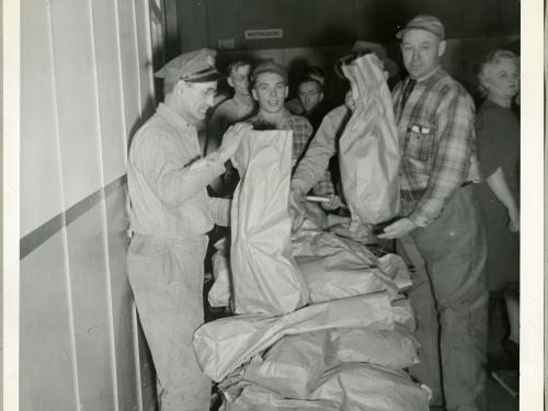 Employees of the Northwestern Aeronautical Corporation line up behind a stand of turkeys that are being given away.