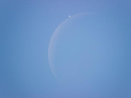 View of the daytime sky as the Moon is just about to block the view of Venus.