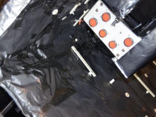 Sheets of black-colored material attached to double-sided tape are applied as part of restoring the Apollo Telescope Mount. Here, the black-covered material is placed as part of the cover of the spar.