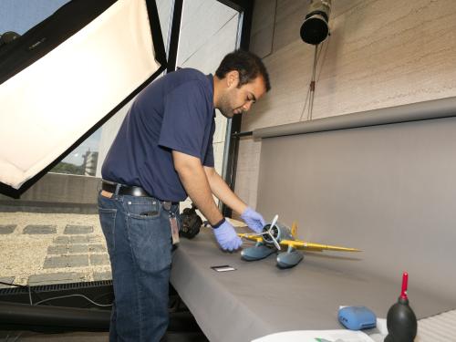 A Museum photographer moves an aircraft model prior to taking photos of the model.