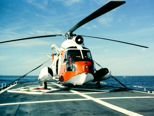 Front view of orange and white Coast Guard helicopter with three-blade rotor.