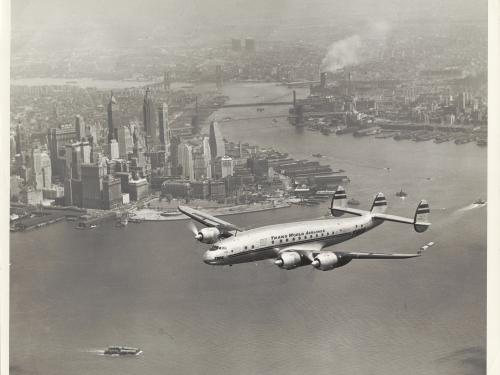 View of commercial aircraft in flight near a city.