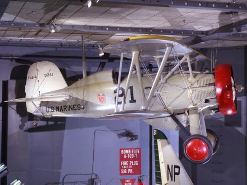 A silver biplane with red wheels and a red circle from which the propeller is mounted. The words "U.S. Marines" are on the side.