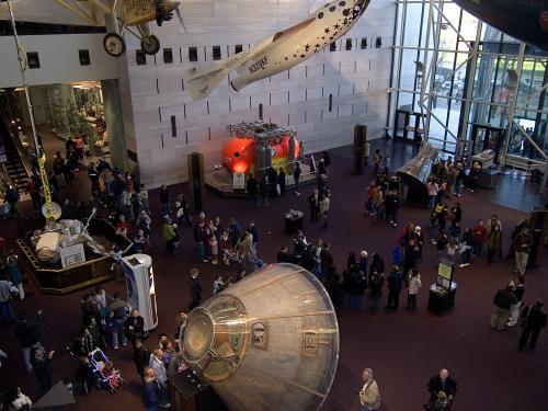 A museum exhibit with aircraft and spacecraft scattered across the floor and attached to the ceiling.