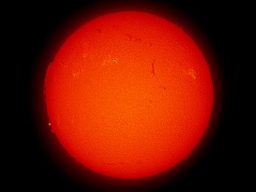 Disk view of the Sun with two visible sunspots and a large prominence of plasma rising from the Sun's surface on the left side of the disk.