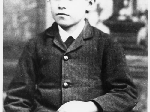 Black and white portrait of a boy sitting in a chair.