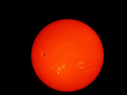 Disk view of the Sun's atmosphere. Sunspots (seen as dark spots) and phages (lighter-colored clouds) are visible on the disk.