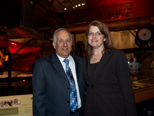 George and Nina Cois, a couple consisting of a white male and a white female, pose together at a reception.