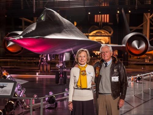 Richard and Anne Jones, a couple consisting of a white man and woman, pose together in front of the Blackbird on display in the Museum.