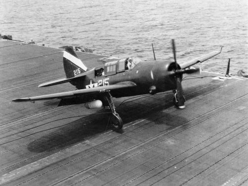 Side view of a monoplane with one engine parked on an naval aircraft hangar. 