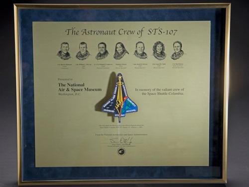 A plaque honoring the members onboard the Space Shuttle Columbia during the STS-107 disaster with their faces and a depiction of the shuttle engraved into the plaque.