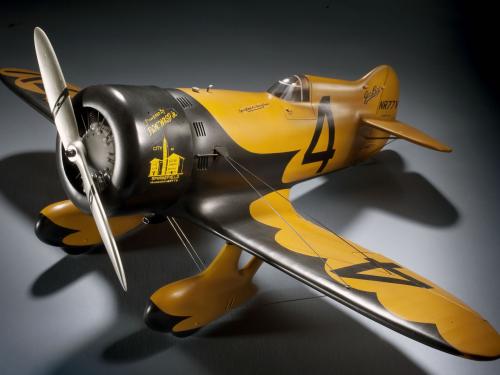 Yellow and black monoplane model with one engine and fixed landing gear. The number four is painted numerically on the left wing and on the side behind the cockpit