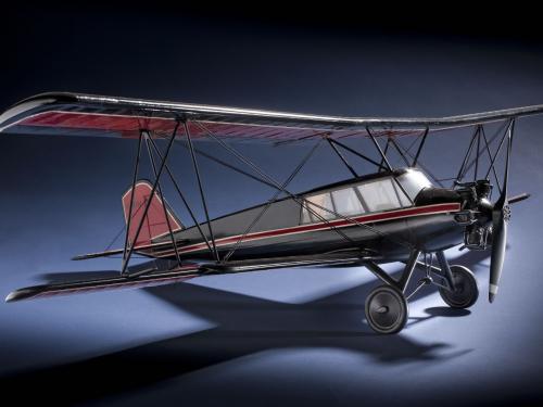 Side view of red and black biplane model with one engine. 