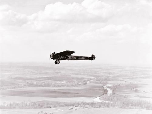 The T-2, a monoplane which attempted the first transcontinental flight, flies above land.