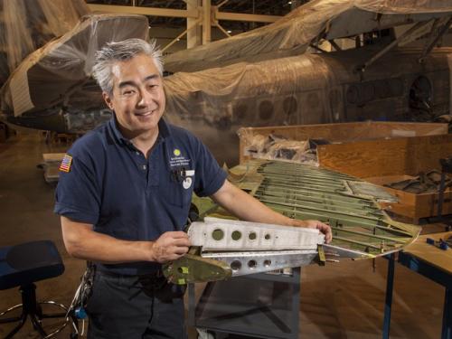 A male museum specialist holds a rubber object he made.