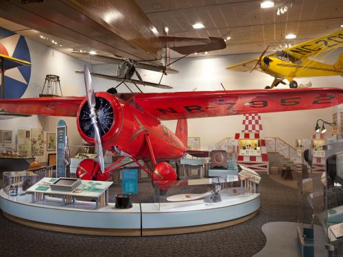 Front view of red monoplane with one engine. Registration number "NR7952" is painted on the lower side of the right wing.