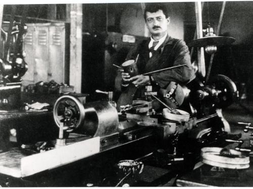 Hermann Julius Oberth, a white man, stands behind a table with primitive rocket parts.