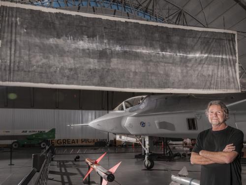 Jacques Garnier, white male co-photographer artist of "The Great Picture", stands in front of the large photo.