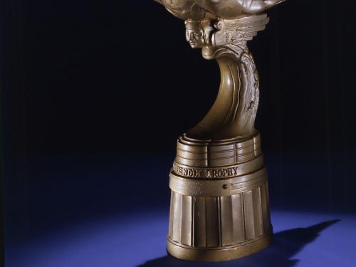 Side view of bronze-colored metal trophy with oblong topper shape.