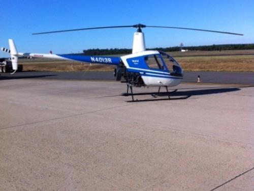 Side view of white and blue helicopter with two propellors at the top. Registration number "N4013R" painted in white on front of tail.