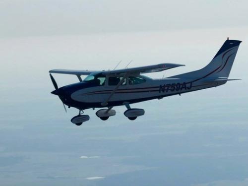 Side view of white monoplane in flight. Monoplane has single engine and fixed landing gear.