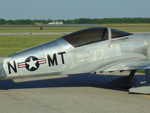 Side view of silver monoplane with one engine and fixed landing gear.