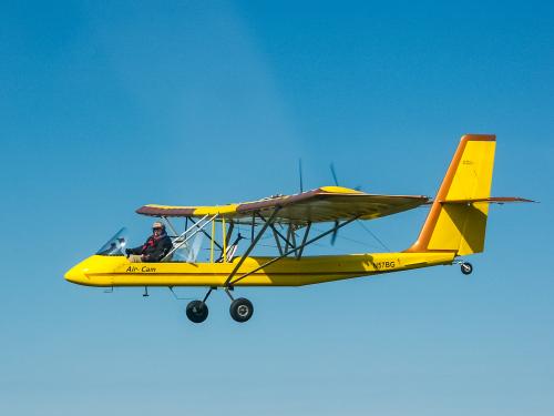 Side view of yellow and red biplane in flight.