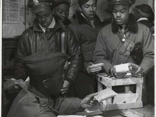 A group of Tuskegee Airmen, who were African-American male pilots during World War II, work on putting escape kits together.