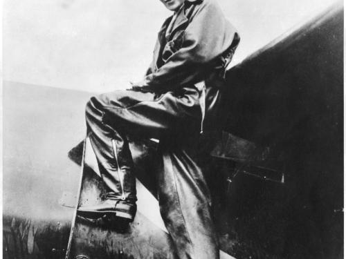 Amelia Earhart, a white woman, climbs into the cockpit of a plane.