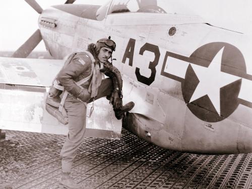 Lt. Edward M. Thomas, an African-American Tuskegee Airman, sits on the wing of an aircraft.