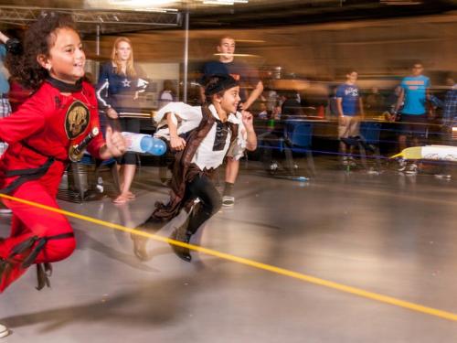 Two kids wearing Halloween costumes participate in a rocket activity during a Halloween event at the Museum.