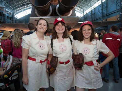 Three women wearing baseball costumes inspired by the movie "League of Their Own" pose together at the Museum's annual Halloween event.