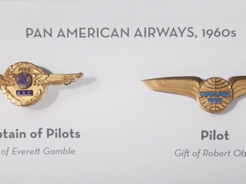 Set of two badges given to the captain of pilots, on the left, and a pilot, on the right, of Pan American Airways in the 1960s. The badges both are gold-colored and have a circle shape surrounded by stylized wings.