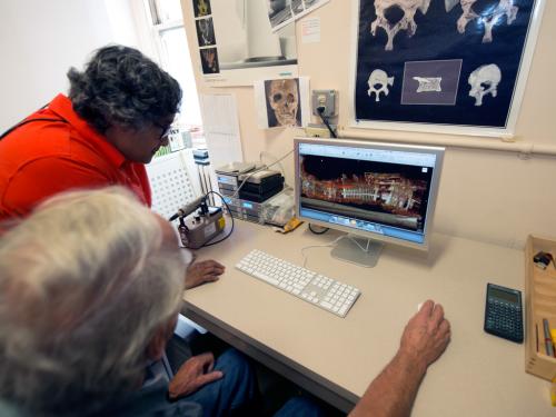 Two Museum staff members look at a CT scan of Neil Armstrong's spacesuit on a desktop computer.