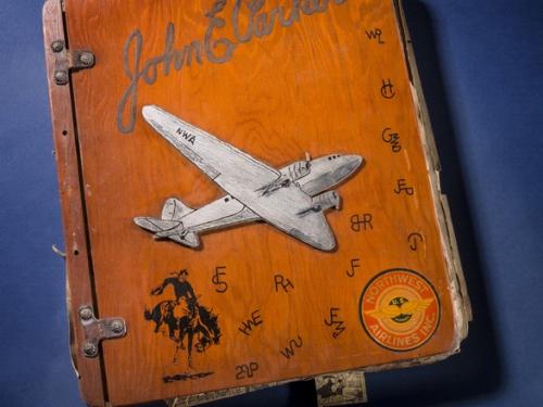 Wooden-colored scrapbook cover featuring a white aircraft. The scrapbook owner's name is written in cursive above the aircraft.